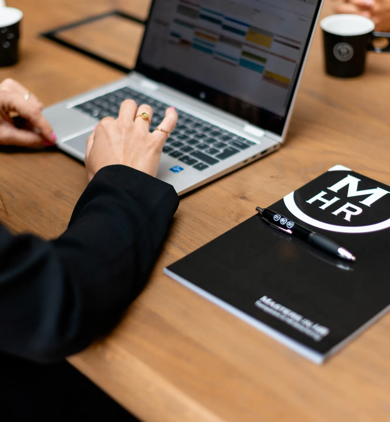 Aan het werk achter de laptop. Masters in HR notitieboek
